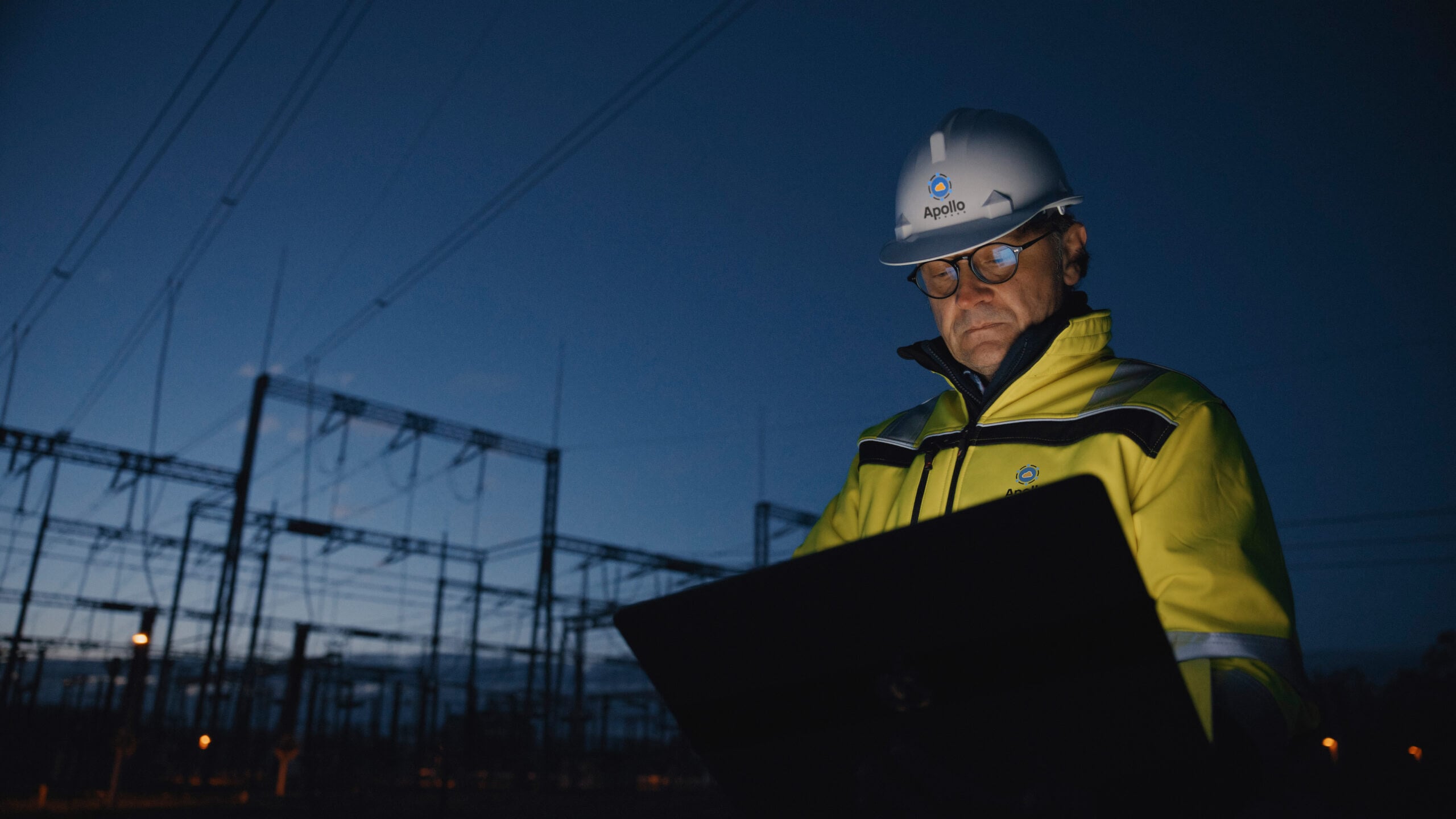 Male electrical engineer works on his laptop at a data center construction site. 