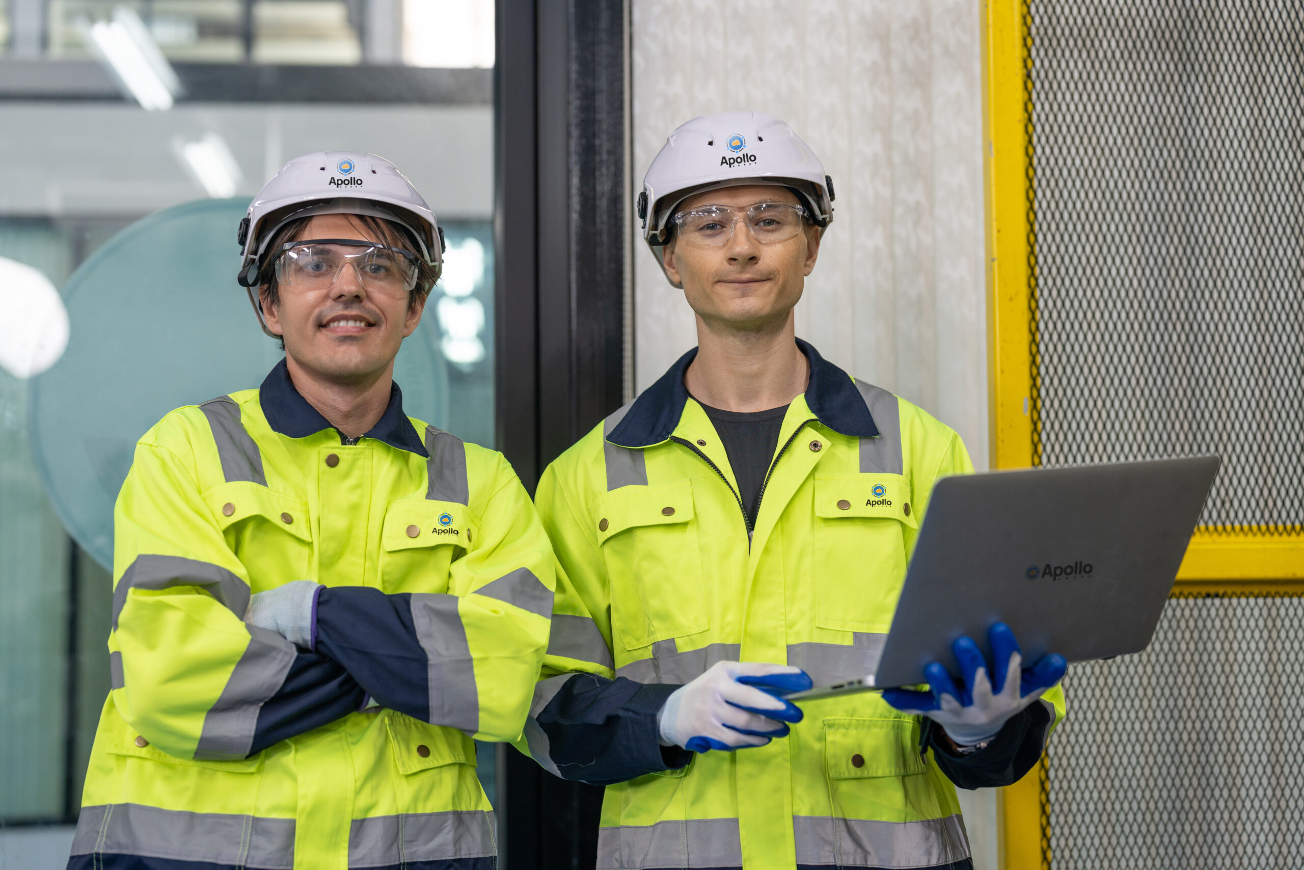 2 male engineers wearing PPE at a data center job site reviewing project on laptop.